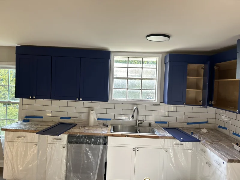 Restored and painted kitchen cabinets after rehanging and corrective repairs.