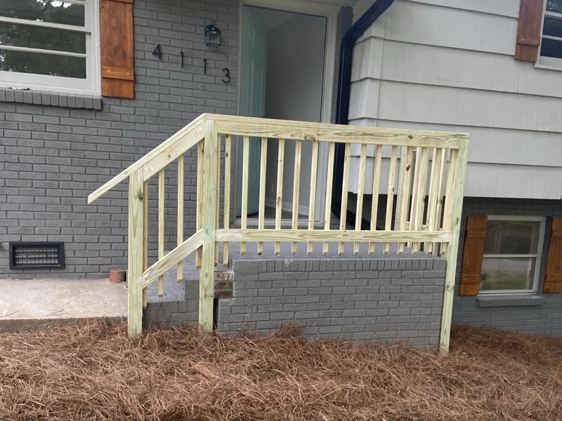 New front entry railing with hand-built shutters and restored windows on a brick home.
